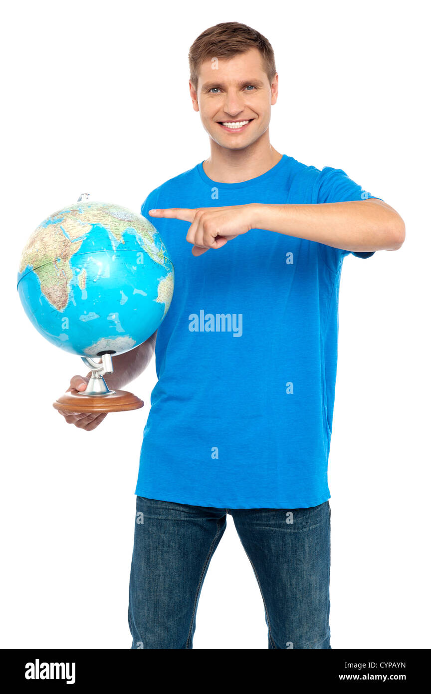 Raffreddare Casual guy puntando al globo rotante isolate su sfondo bianco Foto Stock