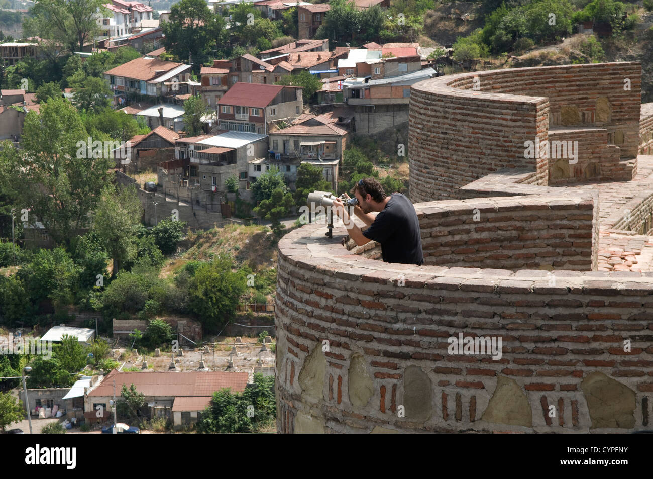 Un turista sulle antiche mura della fortezza di Narikala affacciato su Tbilisi, capitale della Repubblica di Georgia Foto Stock