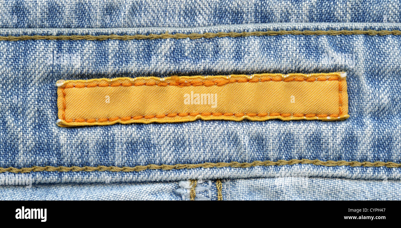 Bianco Giallo etichetta tessili cuciti su un jeans blu. Può essere utilizzato come sfondo per il testo. Foto Stock