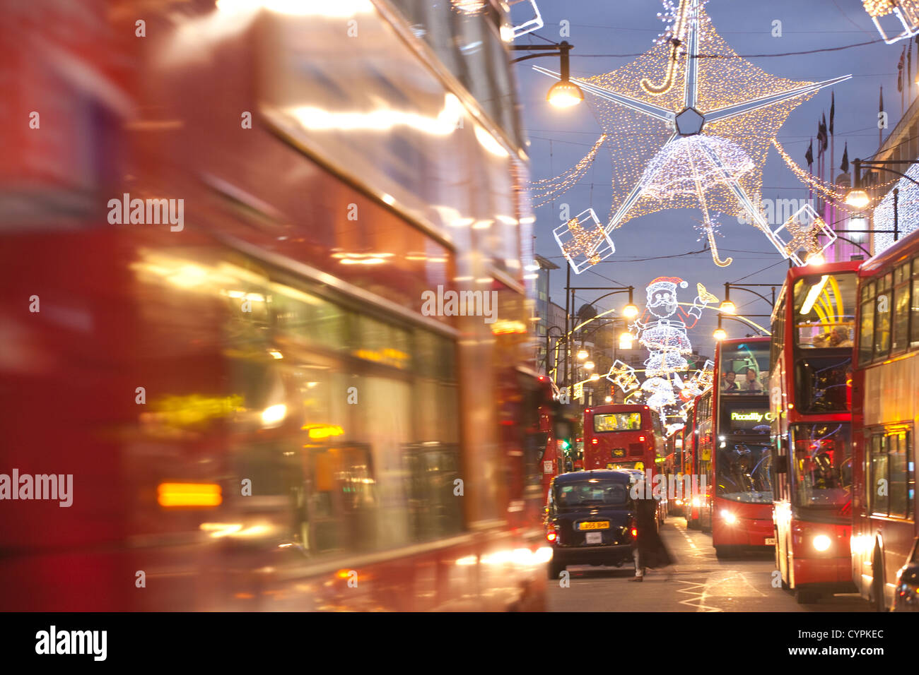 Le luci di Natale durante le ore di punta al tramonto su occupato Oxford Street, Oxford Circus, nel West End di Londra, Inghilterra, Regno Unito Foto Stock