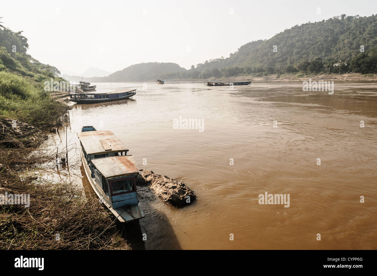 Barche sul fiume Mekong Luang Prabang Laos // LUANG PRABANG, Laos - le tradizionali barche in legno sono attraccate lungo le rive del fiume Mekong in questa città patrimonio dell'umanità dell'UNESCO. Il fiume Mekong funge da percorso di trasporto vitale attraverso Luang Prabang, collegando le comunità lungo la sua vasta rete che scorre attraverso sei paesi del sud-est asiatico. Queste navi in legno sono comunemente utilizzate per il trasporto locale, la pesca e il commercio fluviale nella regione. Luang Prabang, situata alla confluenza dei fiumi Mekong e Nam Khan, è stata dichiarata patrimonio dell'umanità dell'UNESCO nel 1995 per il suo intestino Foto Stock