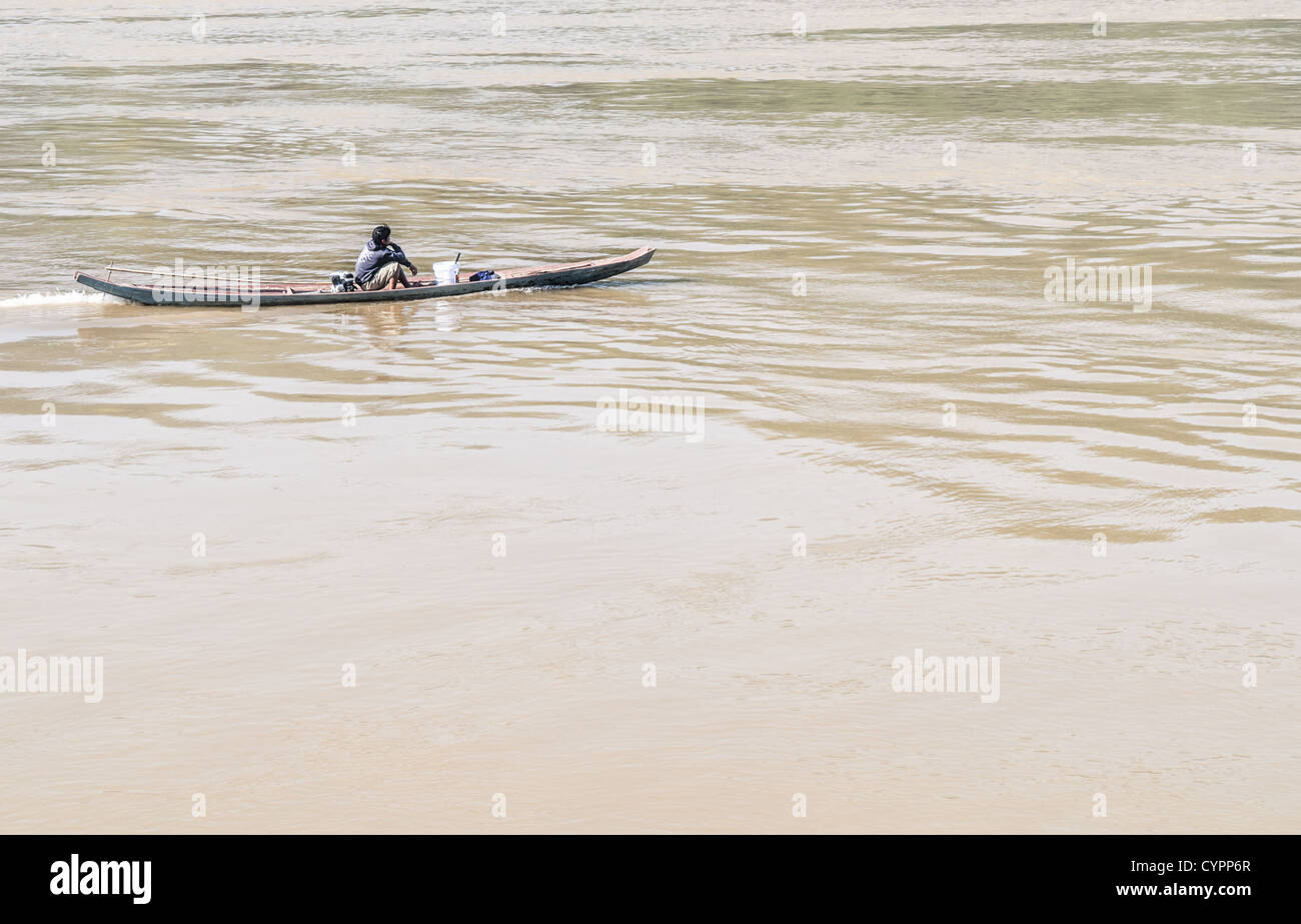 Fiume Mekong Sampan Boat Luang Prabang Laos // LUANG PRABANG, Laos — Un giovane motore il suo sampan lungo il fiume Mekong vicino a Luang Prabang nel Laos centrale. La nave motorizzata stretta rappresenta l'evoluzione delle tradizionali canoe in ciambella, dotate di un piccolo motore a coda lunga spesso assemblato da parti disponibili. Queste imbarcazioni compatte sono comunemente utilizzate dalla gente del posto per il trasporto lungo gli affluenti, la pesca in stretti corsi d'acqua e la navigazione nei canali posteriori del fiume. Luang Prabang, un sito patrimonio dell'umanità dell'UNESCO, si trova alla confluenza dei fiumi Mekong e Nam Khan nel nord del Laos. La A. Foto Stock