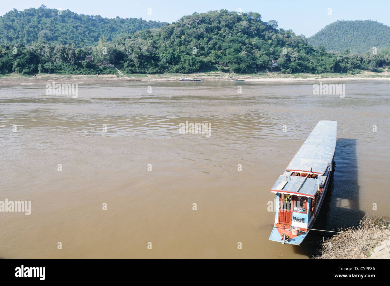 Barche a coda lunga fiume Mekong Luang Prabang Laos // LUANG PRABANG, Laos - grandi barche a coda lunga, conosciute localmente come Hua Hang Thom, sono ormeggiate lungo le rive del fiume Mekong. Queste imbarcazioni tradizionali sono dotate di alberi di trasmissione estesi e sono comunemente utilizzate per viaggi fluviali di media e lunga distanza in tutto il Laos settentrionale. Le barche includono spesso tettoie e posti a sedere per più passeggeri, che servono come taxi fluviali e traghetti locali che collegano le comunità lungo il canale. Luang Prabang, un sito patrimonio dell'umanità dell'UNESCO, si trova alla confluenza dei fiumi Mekong e Nam Khan nel nord di L Foto Stock