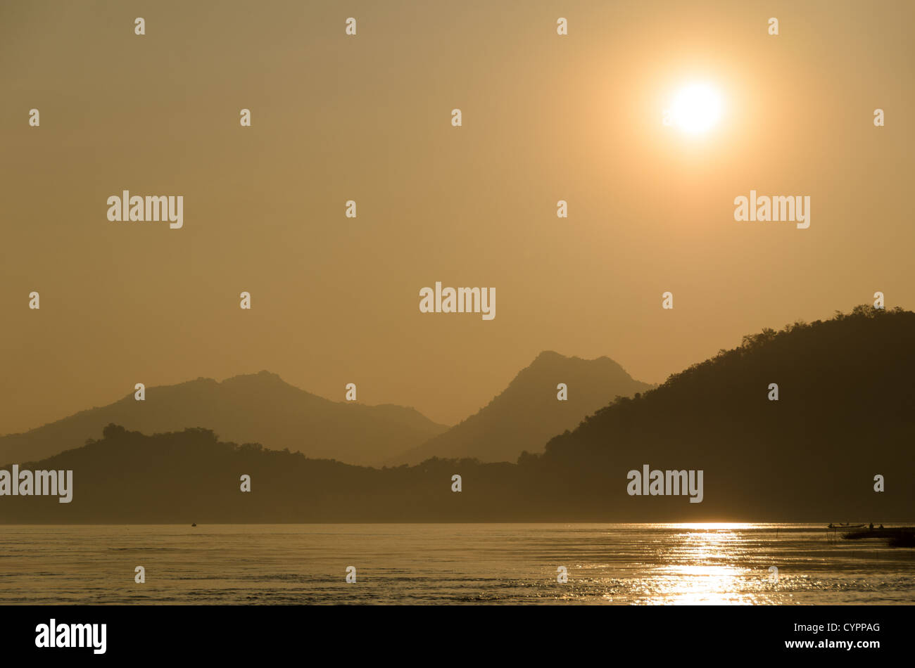 Tramonto sul fiume Mekong Luang Prabang Laos // LUANG PRABANG, Laos - colline e montagne si stagliano contro il tramonto sul fiume Mekong vicino a Luang Prabang nel Laos centrale. Il fiume Mekong scorre attraverso questa città patrimonio dell'umanità dell'UNESCO, che è stata per secoli la capitale reale del Regno del Laos. Luang Prabang si trova alla confluenza dei fiumi Mekong e Nam Khan nel Laos settentrionale, circondato da un terreno montuoso che caratterizza gran parte del paesaggio del paese. La città è ampiamente considerata uno degli insediamenti tradizionali meglio conservati del sud-est asiatico, con una biglia Foto Stock