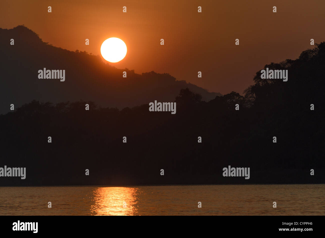 Tramonto sul fiume Mekong Luang Prabang Laos // LUANG PRABANG, Laos - il sole tramonta si riflette sulle acque ondulate del fiume Mekong vicino a Luang Prabang, con sagome di montagna visibili in lontananza. Il fiume Mekong scorre attraverso il Laos settentrionale, fungendo da canale vitale per il trasporto e il commercio nella regione. Luang Prabang, situata alla confluenza dei fiumi Mekong e Nam Khan, è un sito patrimonio dell'umanità dell'UNESCO riconosciuto per il suo patrimonio architettonico e culturale ben conservato. L'antica città servì come capitale reale del regno di Luang Prabang fino al 1975 e remai Foto Stock