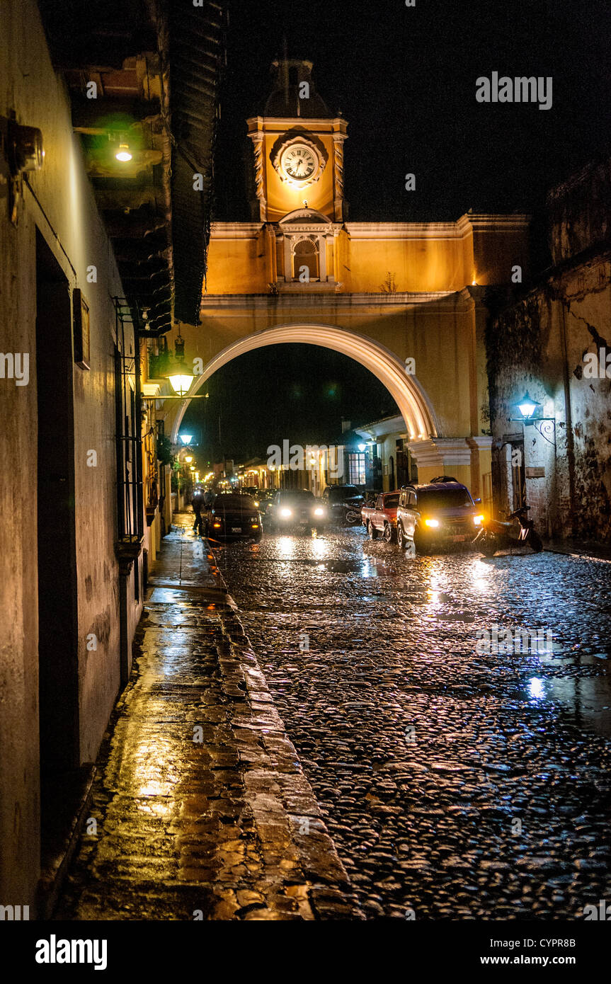 Il portone sulla strada del convento di Santa Catalina nel centro di Antigua, Guatemala, con l'acqua dalle recenti piogge che riflette le luci sulla strada di ciottoli. Foto Stock