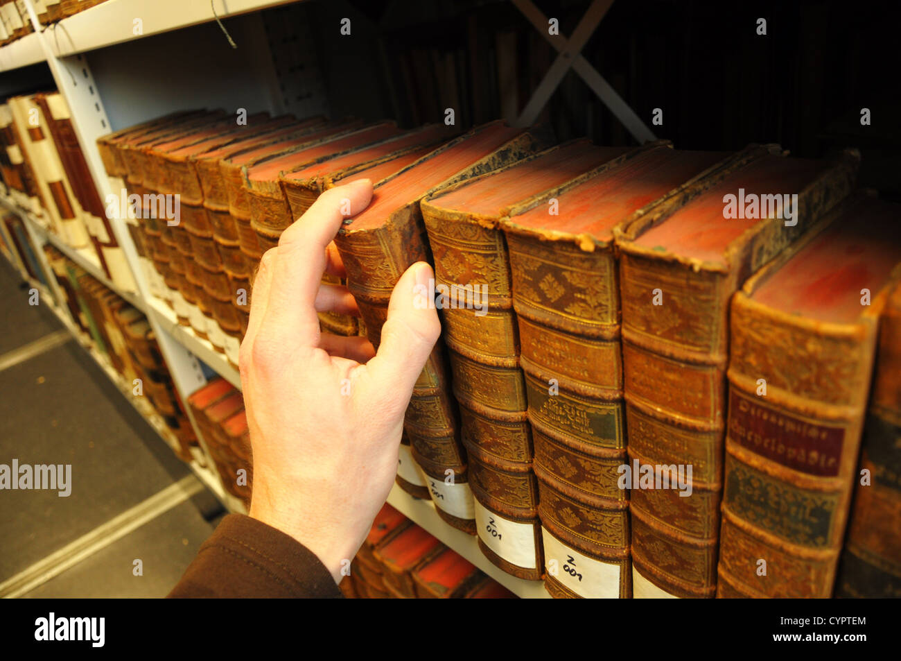 Vecchi libri in una libreria con la mano che mostra il concetto di istruzione Foto Stock