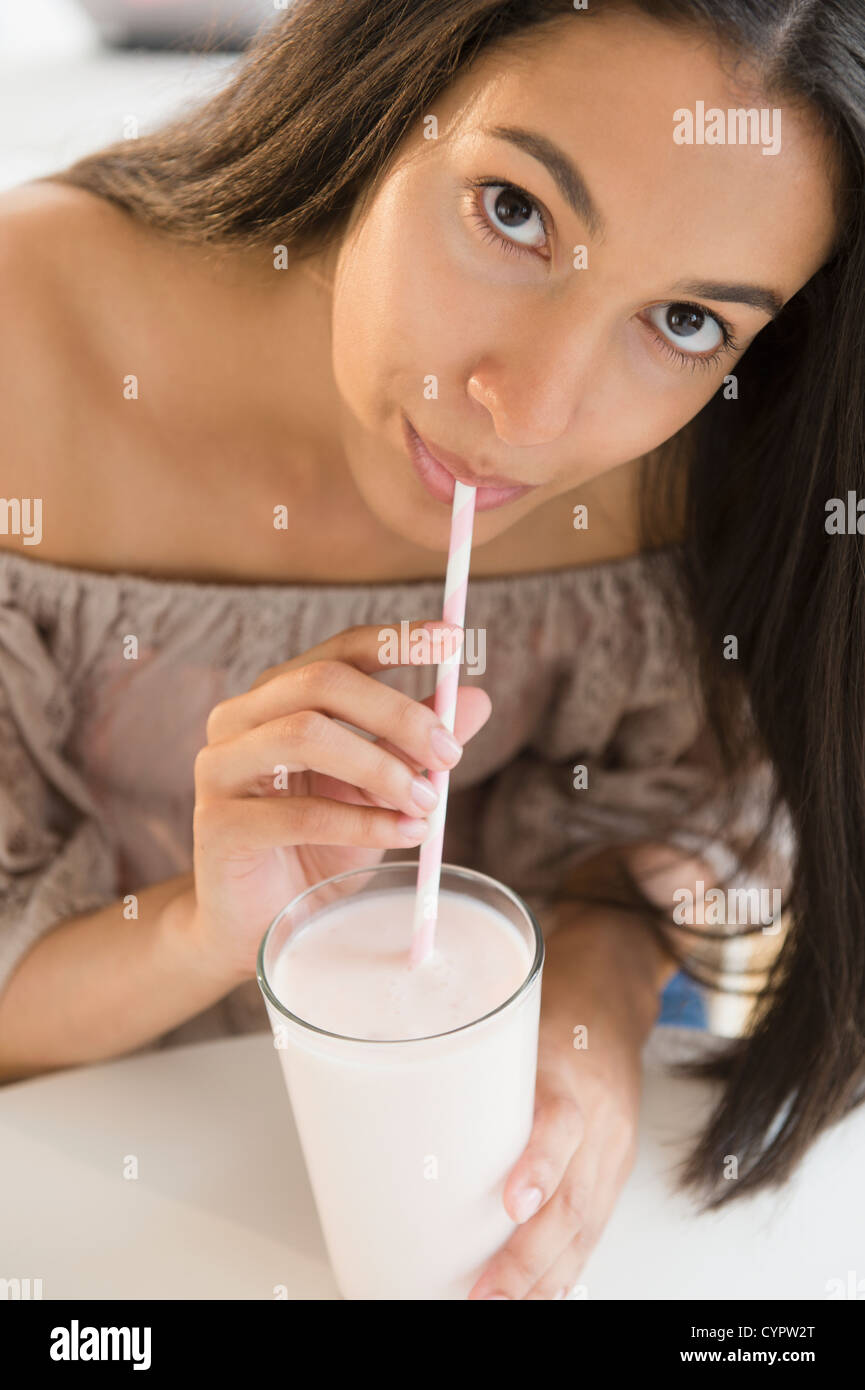 Adolescente ispanica bere latte con paglia Foto Stock