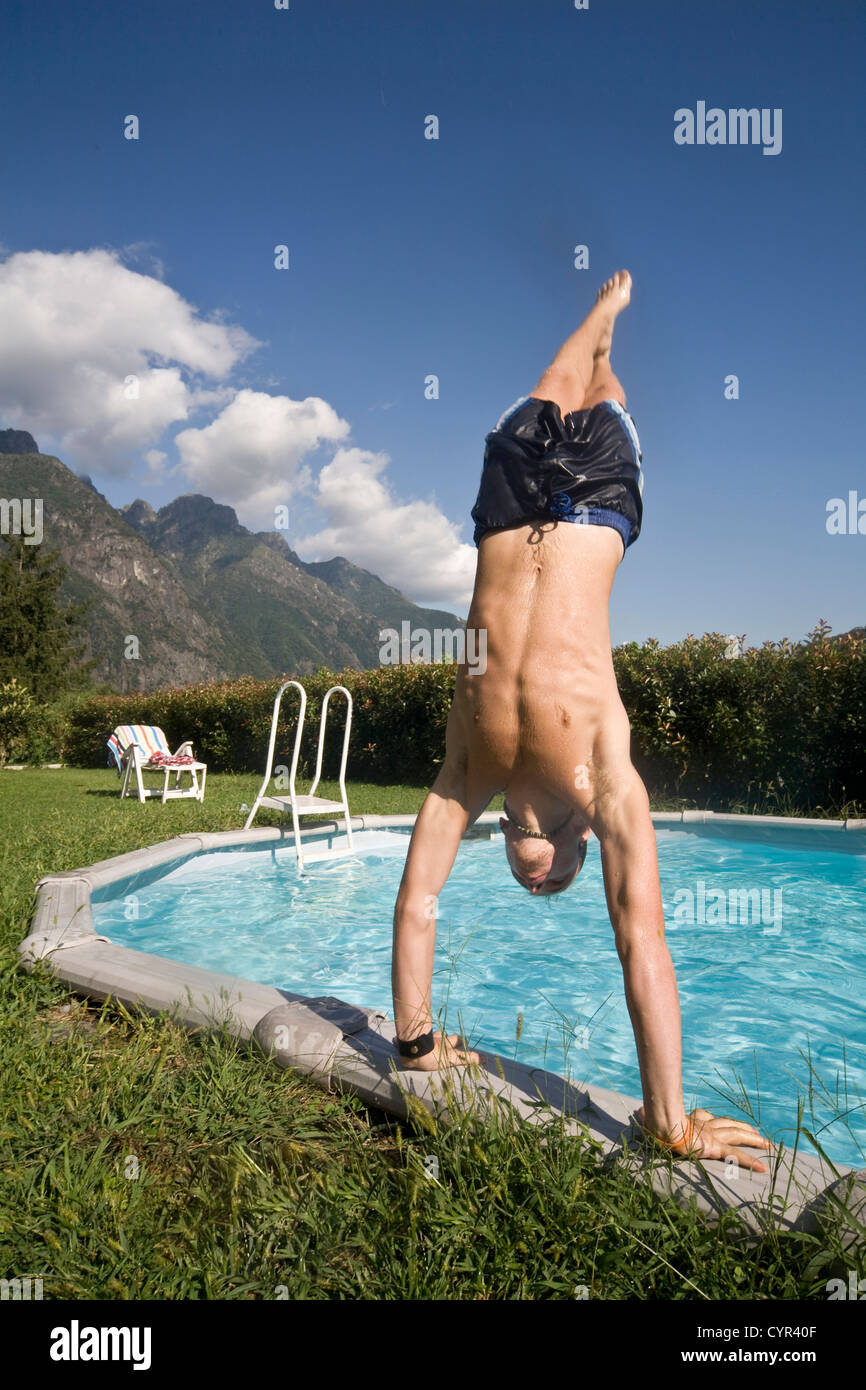 L'uomo facendo handstand sul bordo della piscina Foto Stock