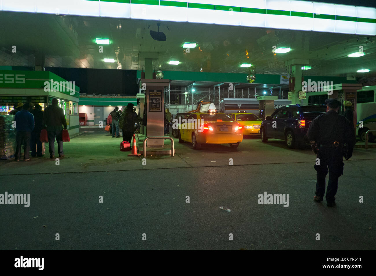 November 8, 2012, New York, NY, USA. Ore prima il razionamento del gas è quello di iniziare a New York City, un funzionario di NYPD mantiene un occhio sui clienti in una stazione di benzina sulla 10th Avenue in Hell's Kitchen. Foto Stock