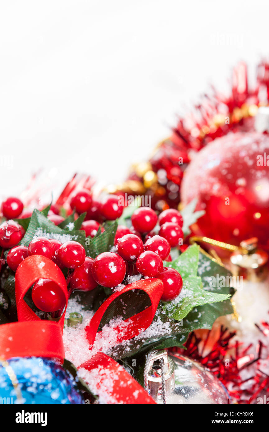 Bordo di Natale con agrifoglio bacche, nastro rosso e ninnolo coperte da neve con copia spazio. Foto Stock