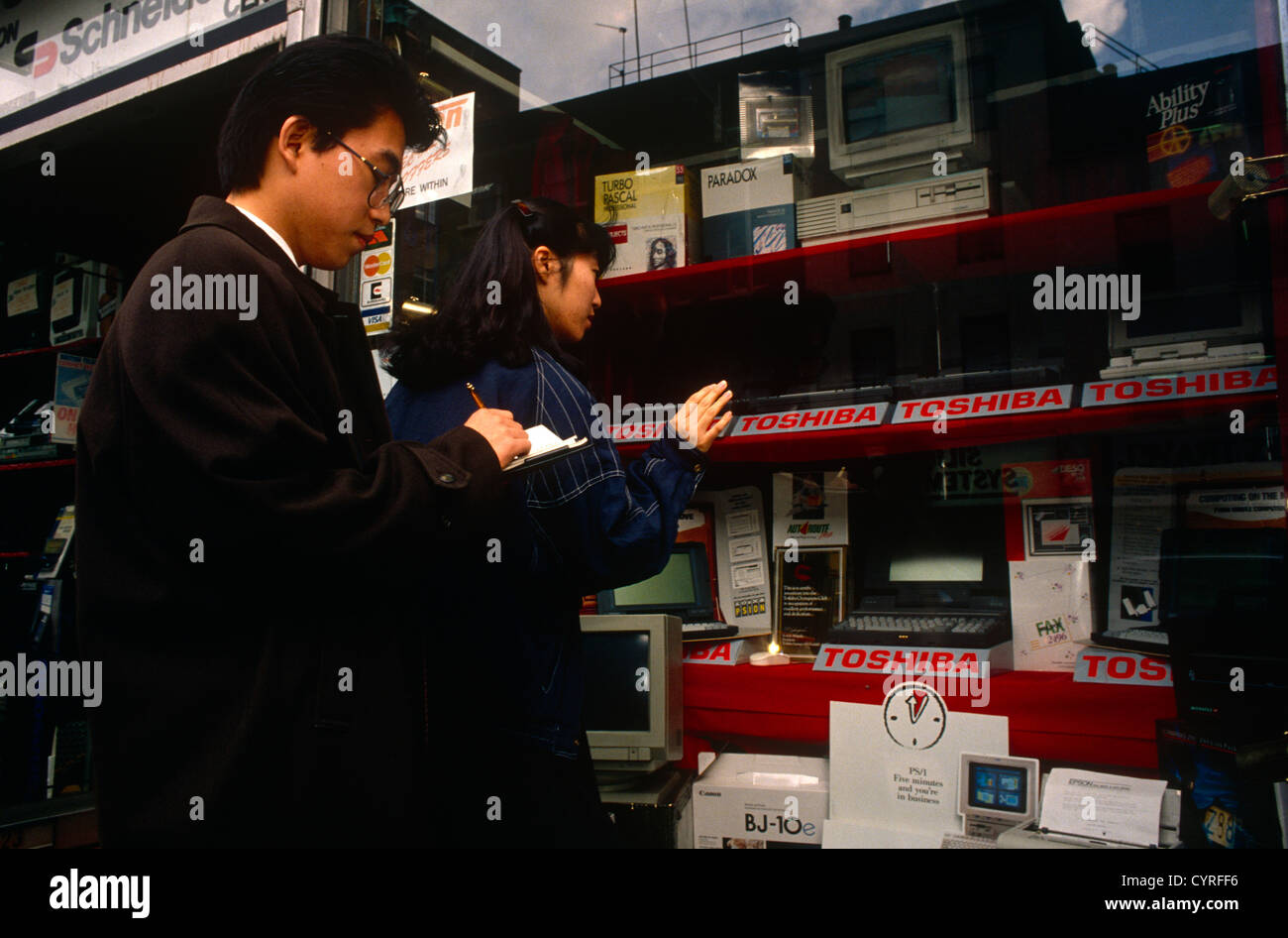 Due persone di East Asian-discesa guardare i portatili Toshiba visualizzati in un computer specializzato in Tottenham Court Road Foto Stock