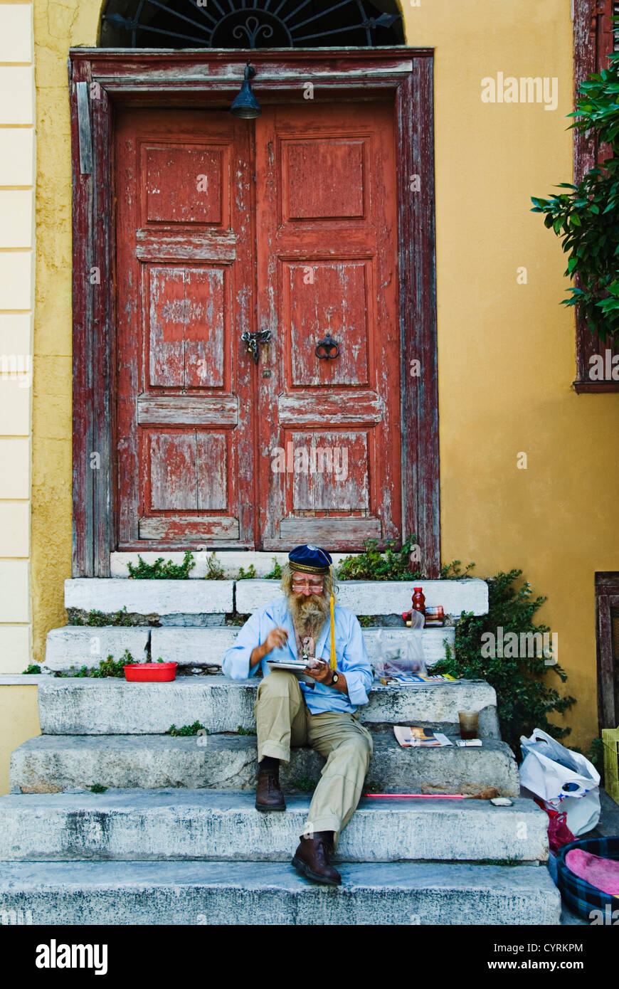 Uomo seduto sui gradini e la pittura, Atene, Grecia Foto Stock