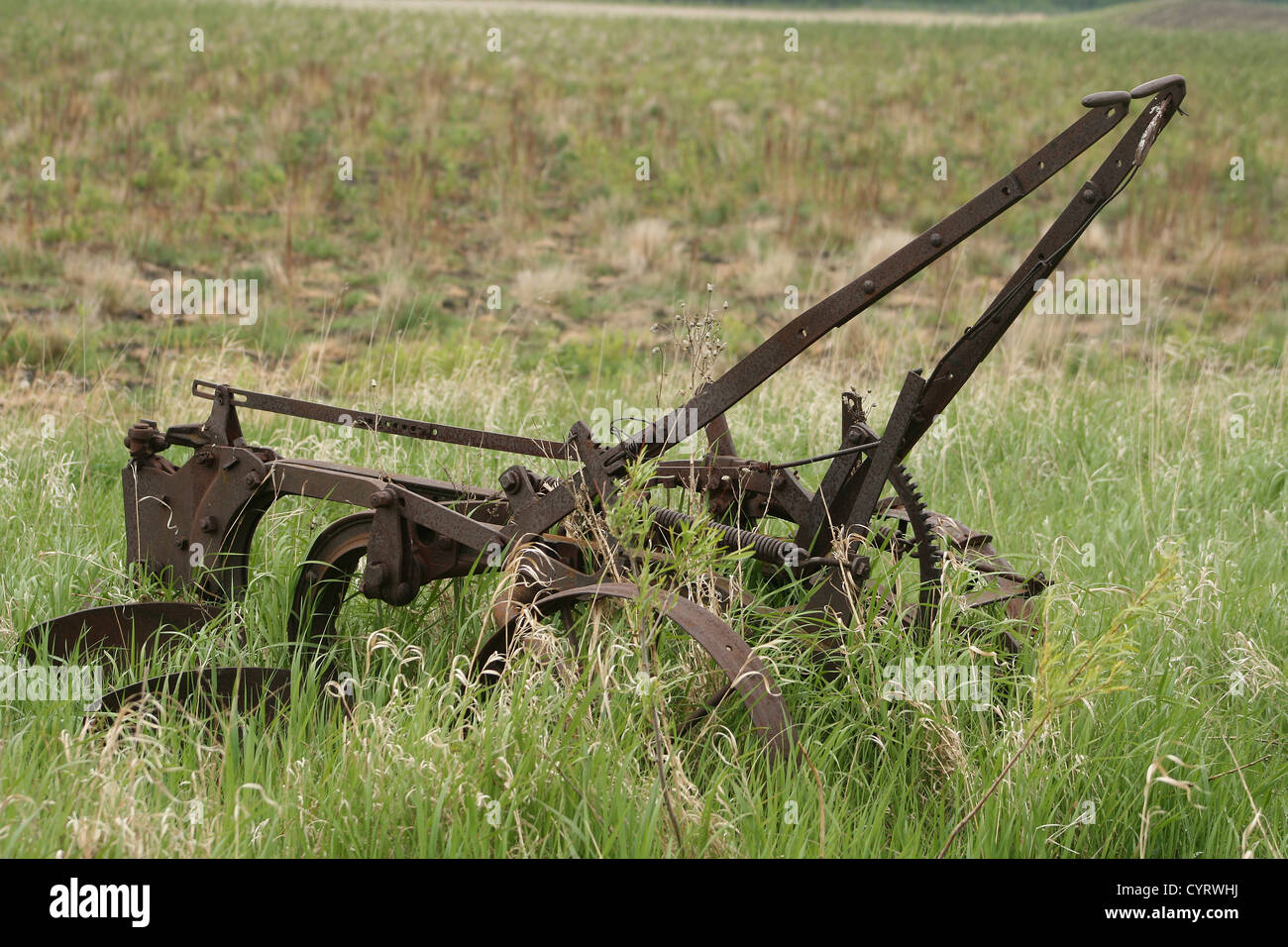 Un antico, coperto di ruggine due condividono un aratro abbandonato in un campo di agricoltori in primavera a Winnipeg, Manitoba, Canada Foto Stock