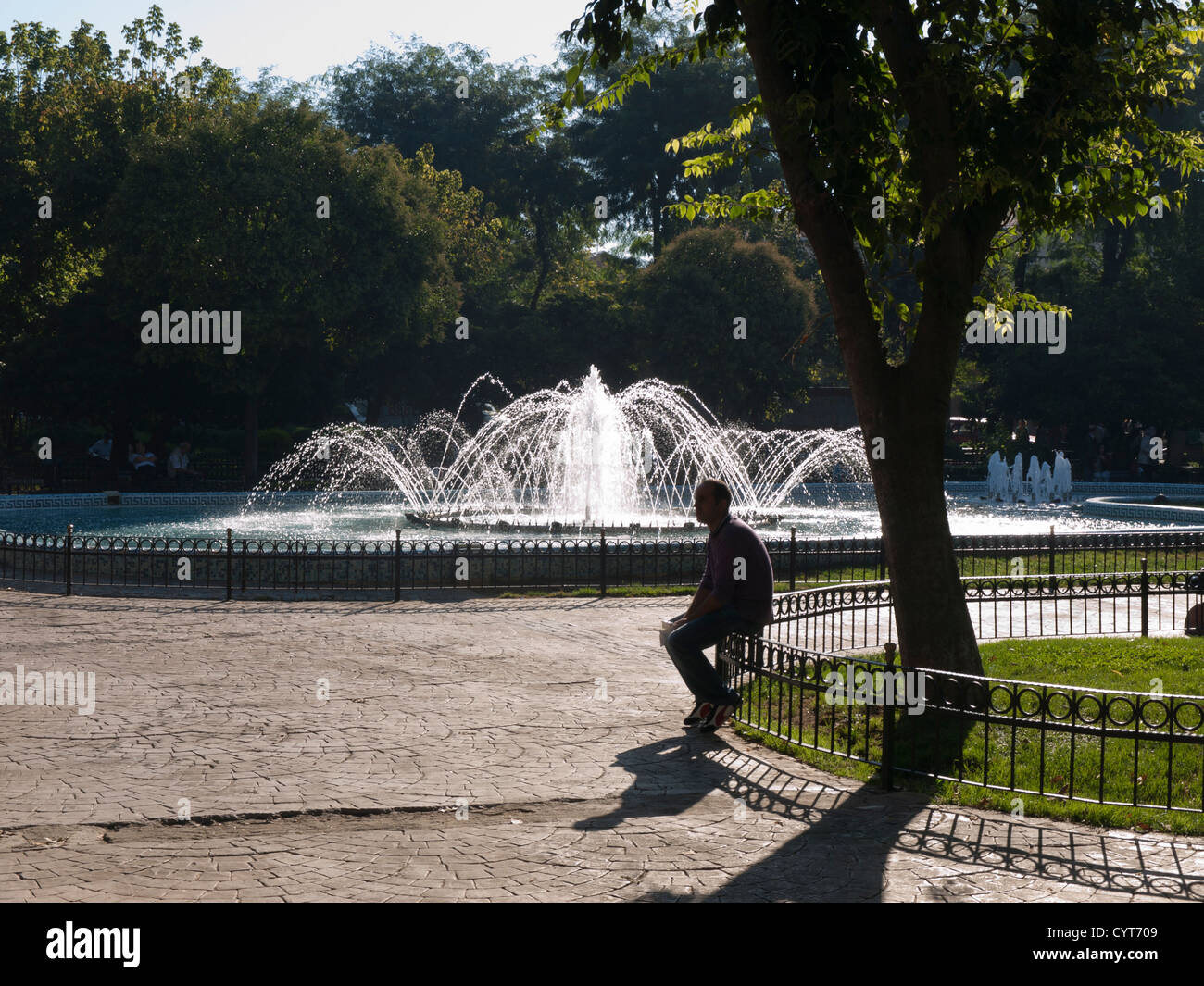 Rilassante in un parco locale con fontana vicino Kumkapi Istanbul Turchia. Una silhouette uomo seduto sulla recinzione Foto Stock