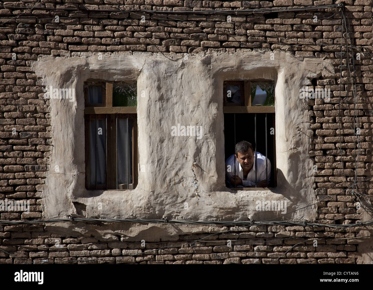 Uomo che guarda fuori dalla finestra di una tipica casa residenziale, sana, Yemen Foto Stock