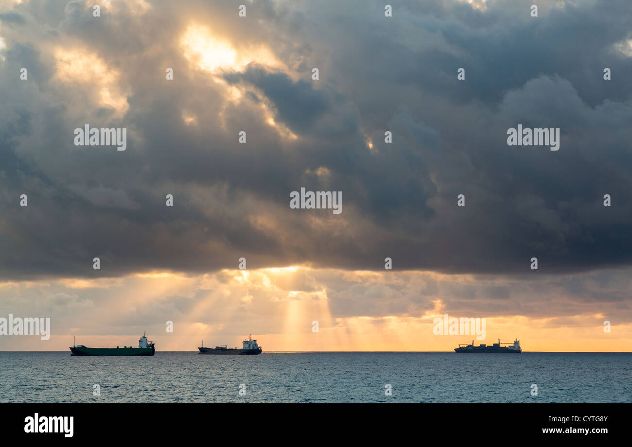 Tre il carico o il nolo di navi per orizzonte al tramonto su nuvoloso burrascosa serata Foto Stock