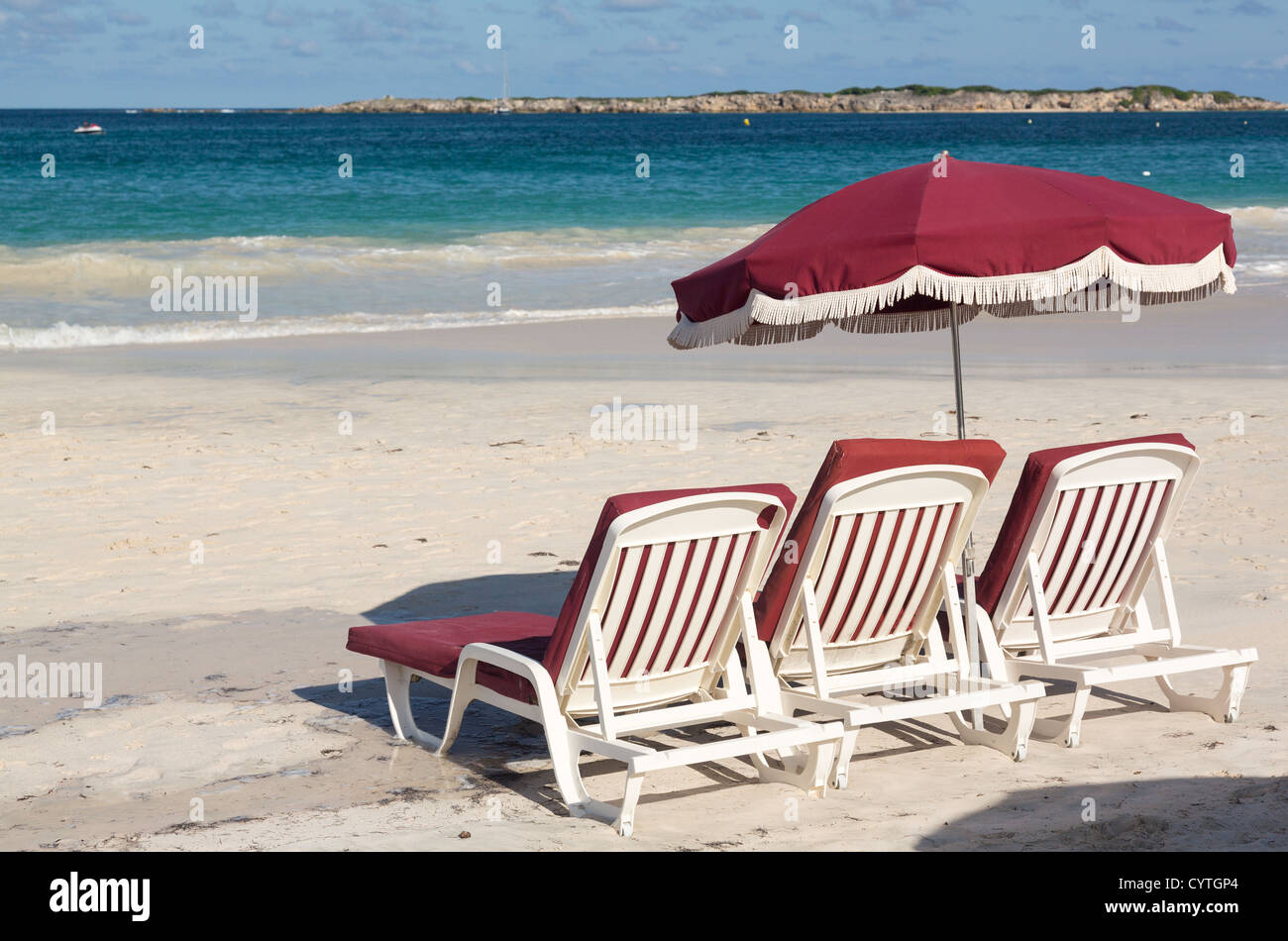 Tre in plastica bianca spiaggia sdraio e ombrellone in Orient Beach St Martin Foto Stock