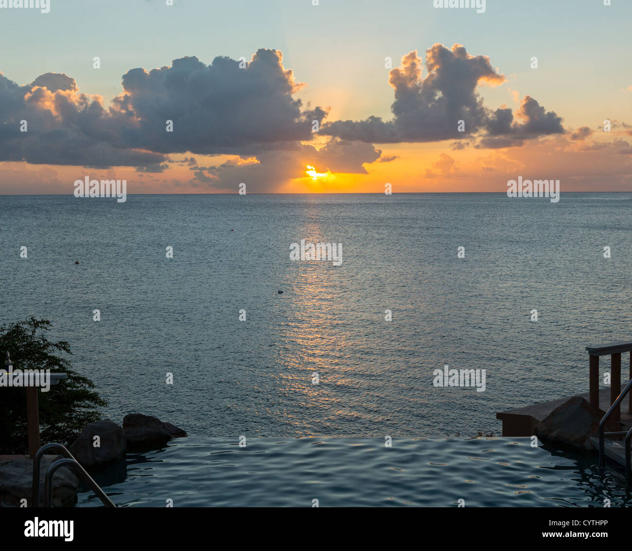 Bordo della piscina a sfioro con vista sull'oceano al tramonto Foto Stock