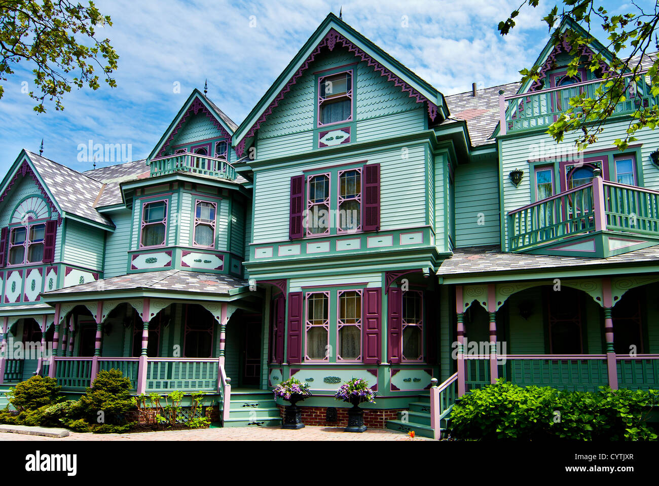 Bella grande vecchio nostalgico legno storico verde con viola Victorian House edificio con portico. Foto Stock