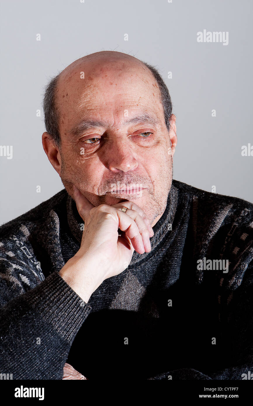 La faccia di un uomo vecchio con po' di capelli e calvo spot e la mano sul suo mento con espressione seria, isolata. Foto Stock