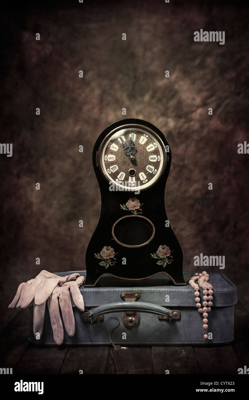 Un vecchio orologio da tavolo in stile Biedermeier con una valigia in pelle, guanti e una collana di perle Foto Stock