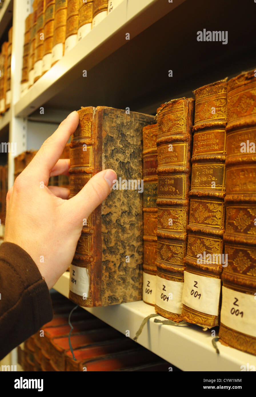 Vecchi libri in una libreria con la mano che mostra il concetto di istruzione Foto Stock