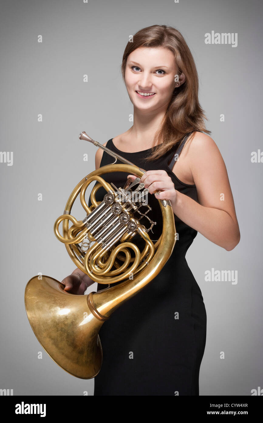 Femmina giovane musicista con concerto corno francese in abito nero Foto Stock