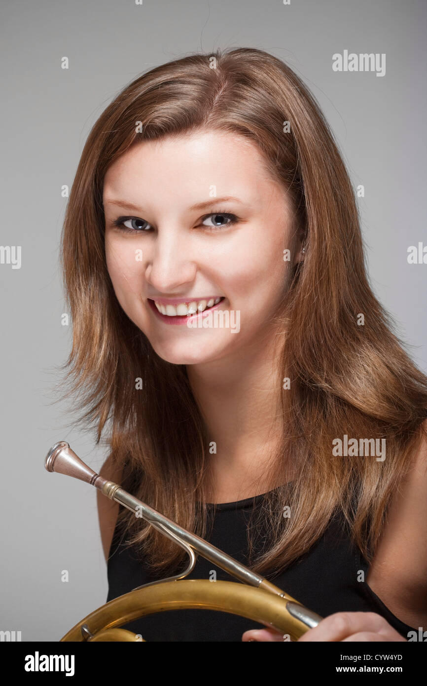 Ritratto di giovane donna musicista con concerto corno francese in abito nero Foto Stock