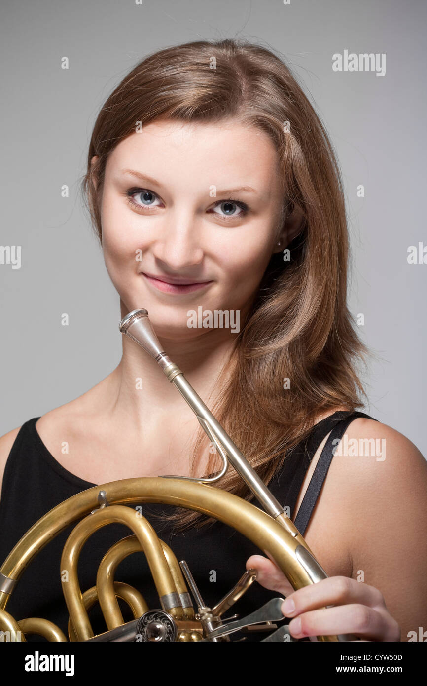 Femmina giovane musicista con concerto corno francese in abito nero Foto Stock