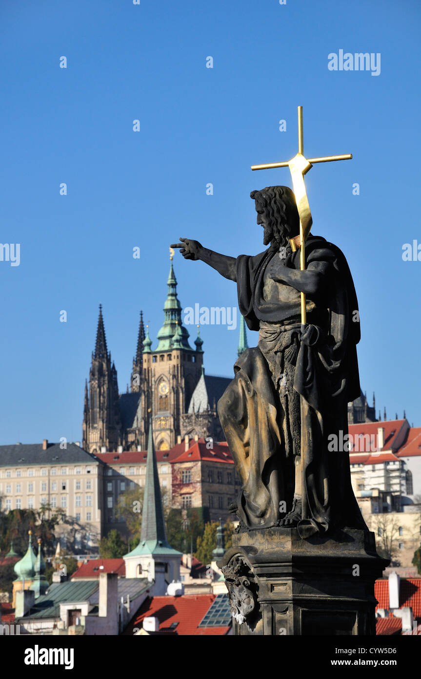 Praga, Repubblica Ceca. Charles Bridge. Statua: San Giovanni Battista - il castello e la Cattedrale di San Vito dietro Foto Stock