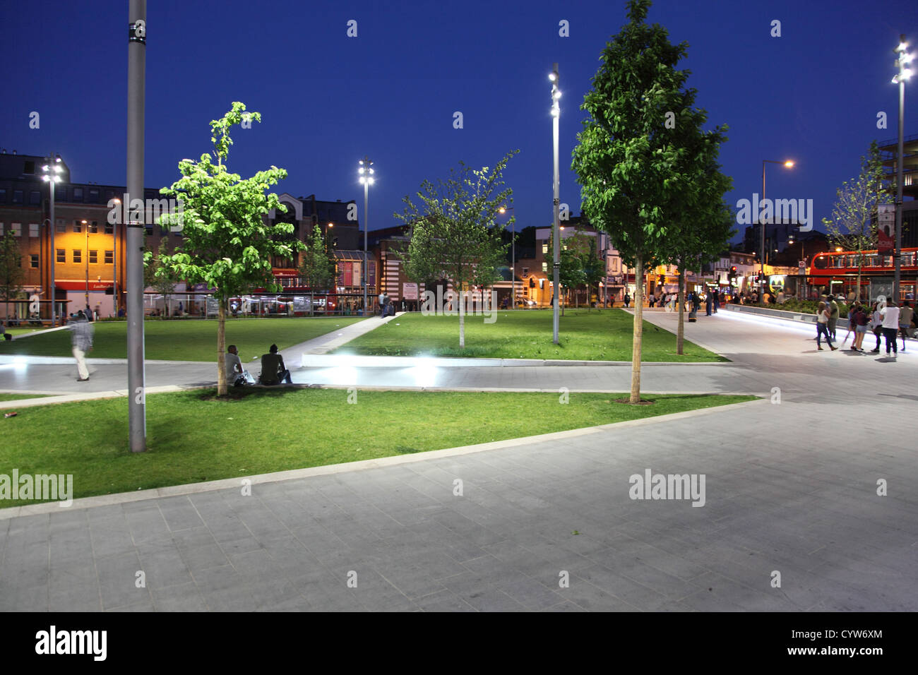 Gordon generale posto, Woolwich, UK. Moderno e paesaggistici town square di notte con ampi marciapiedi, sedili, alberi e aree di erba. Foto Stock
