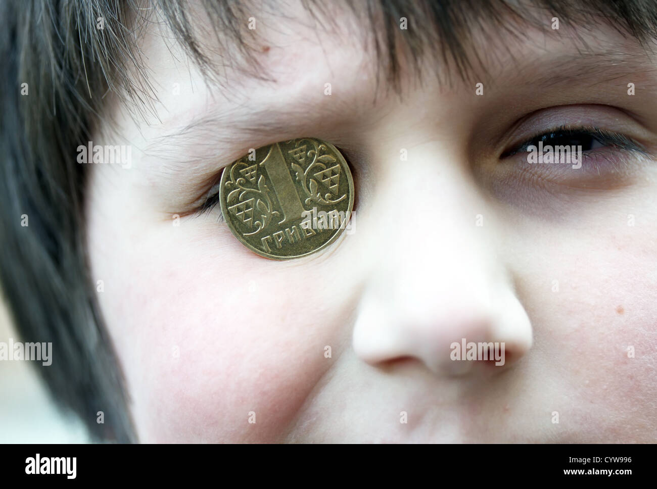 Ragazzo divertente con la moneta ucraina sull'occhio Foto Stock