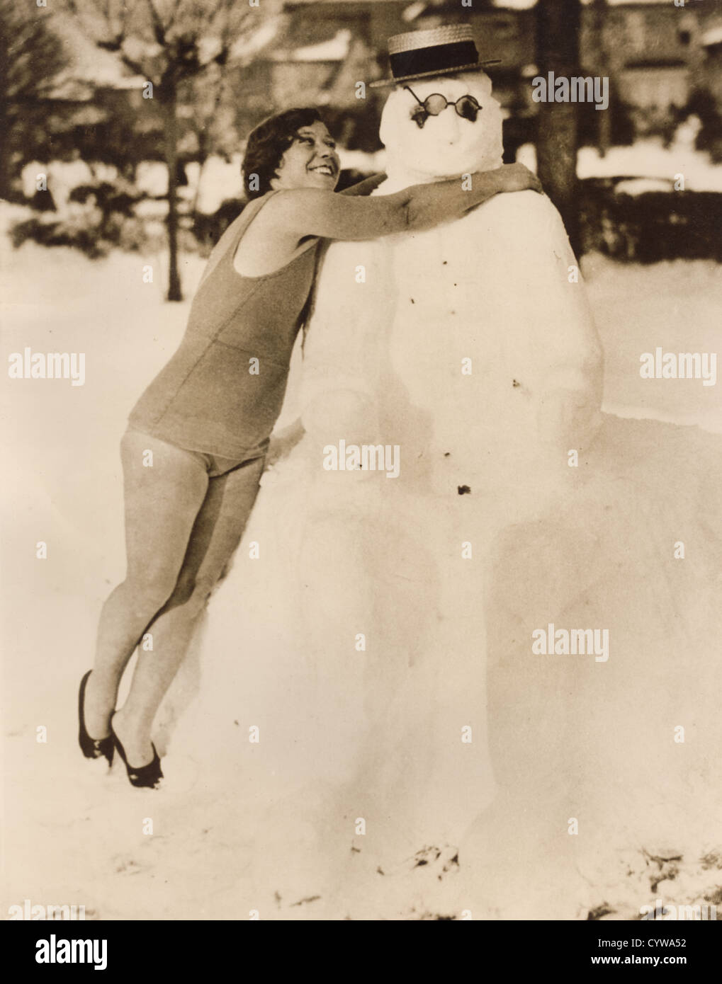 Vintage degli anni Trenta foto per la stampa della giovane donna abbracciando pupazzo di neve prima di andare in acqua per una nuotata, Manhattan Beach, New York, U.S.A. Foto Stock