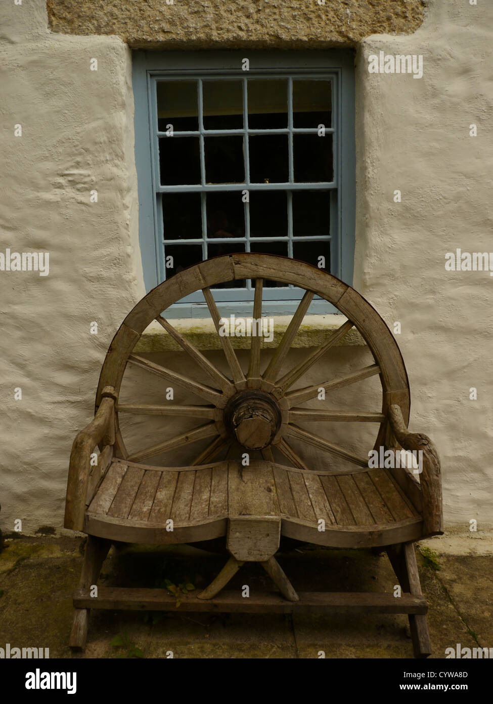 Caratteristico, rustico lime lavato cob cottage con ruota carrello panca, Durgan Cornwall, England, Regno Unito Foto Stock