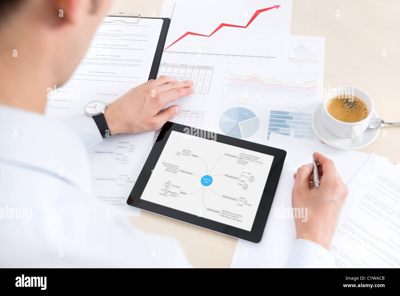 Imprenditore sul luogo di lavoro il lavoro con documenti e utilizzando i moderni digitale compressa. Foto Stock