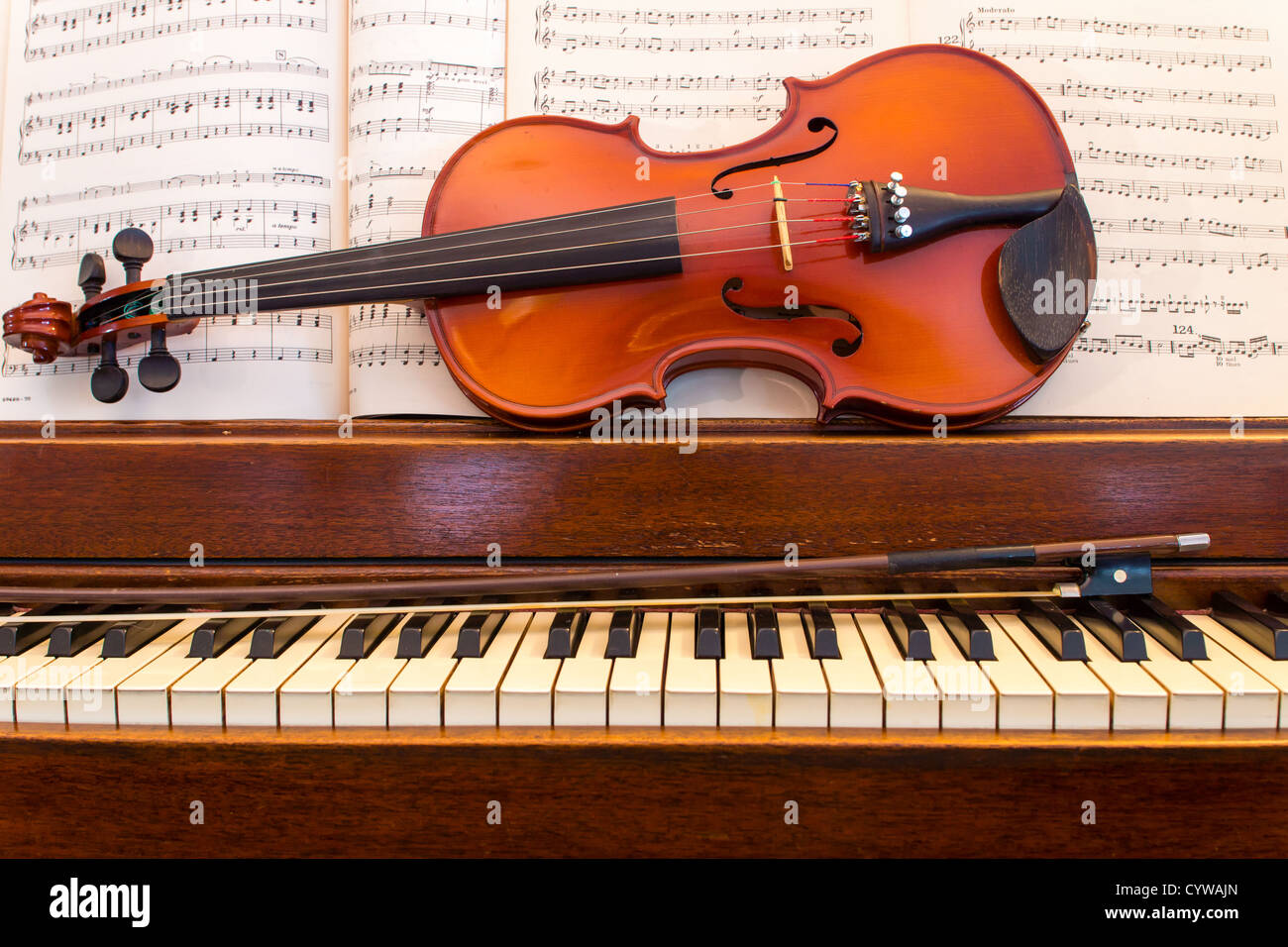 Un vecchio pianoforte in legno si siede con un violino, archetto e foglio  di musica Foto stock - Alamy