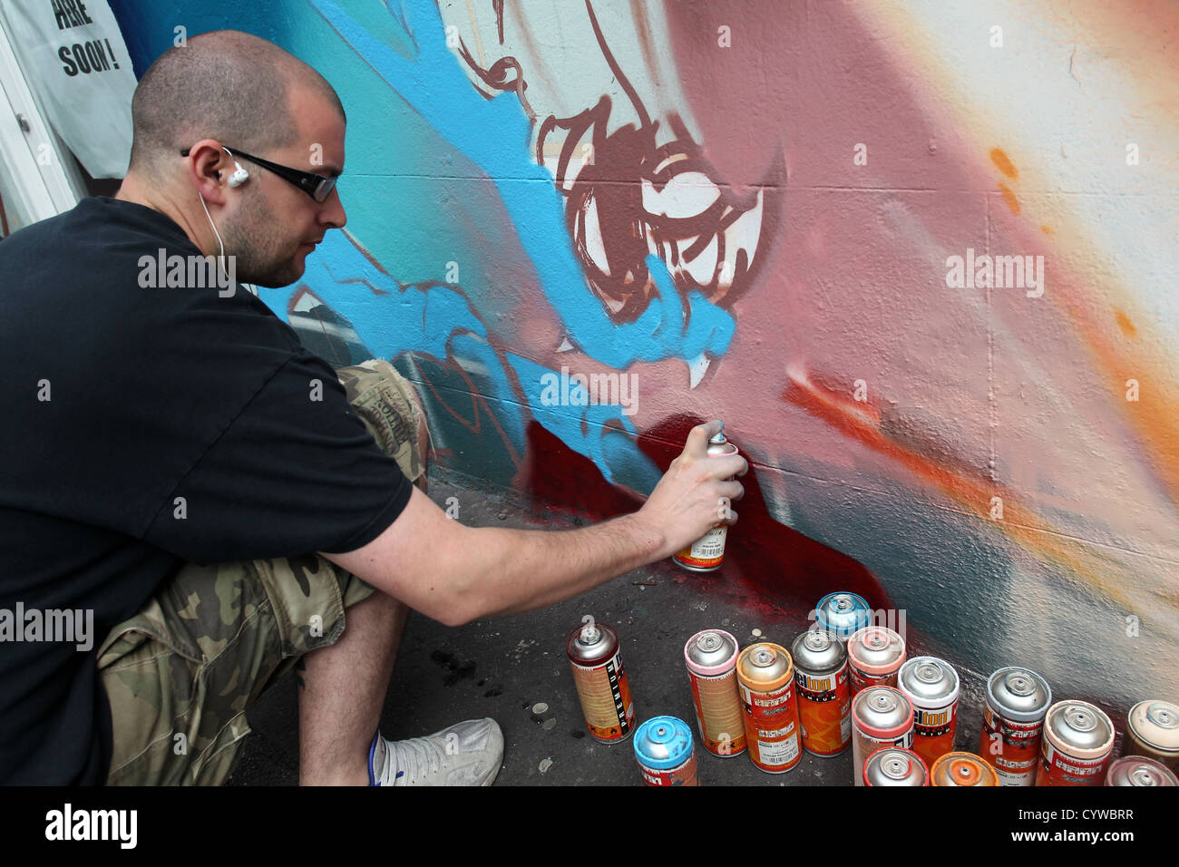 Un artista di graffiti pittura raffigurato su una parete in Brighton, East Sussex, Regno Unito. Foto Stock