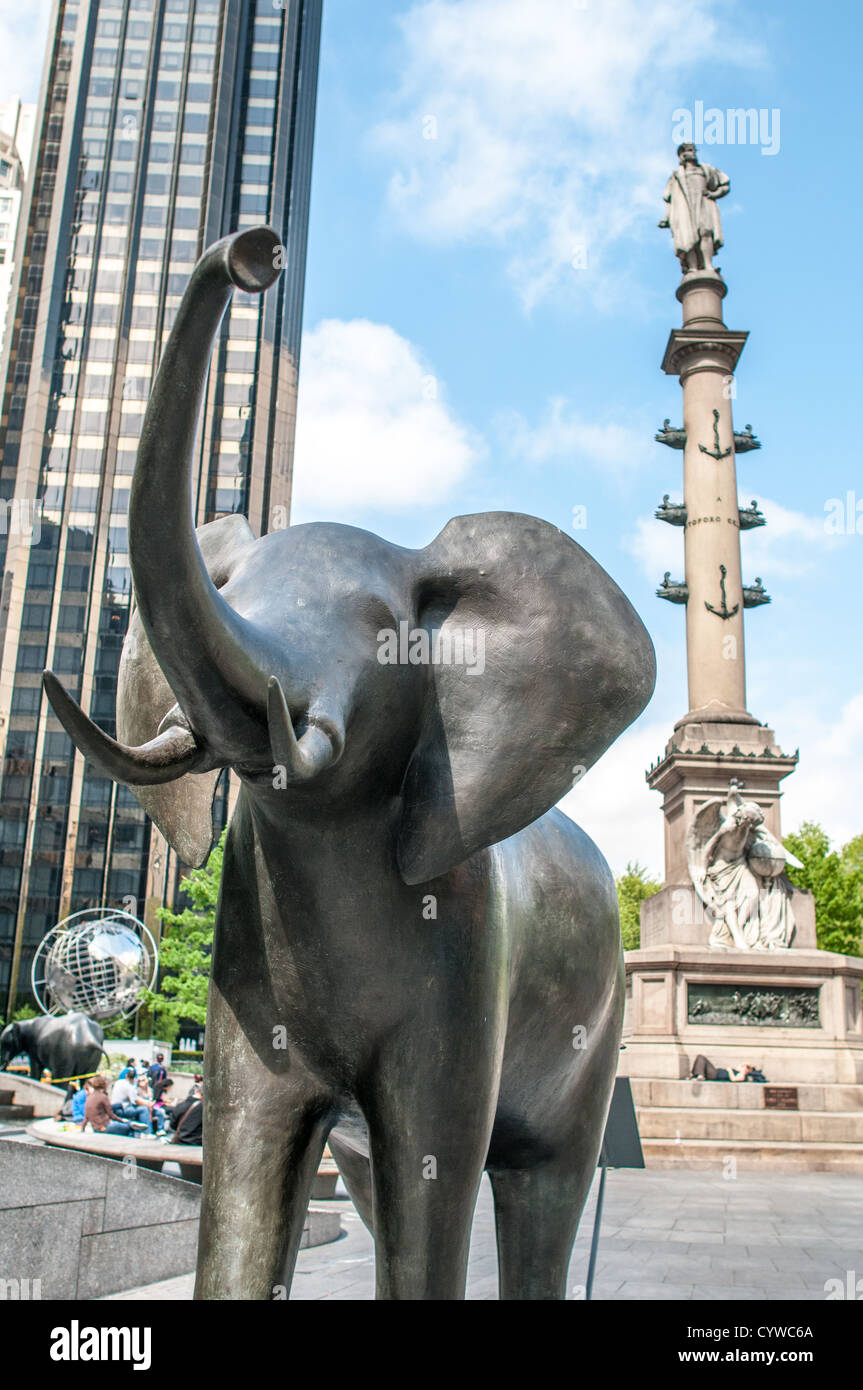 NEW YORK, New York, Stati Uniti: Una scultura di elefante in bronzo a grandezza naturale dell'artista Peter Woytuk si trova in una posizione prominente a Broadway come parte di una mostra d'arte pubblica con la fauna selvatica. Sullo sfondo, sorge l'imponente monumento a Colombo, creando una suggestiva giustapposizione tra il paesaggio urbano e l'installazione artistica naturalistica. Questa mostra unica trasforma la vivace strada in una galleria all'aperto, portando arte e natura nel cuore di Manhattan. Foto Stock