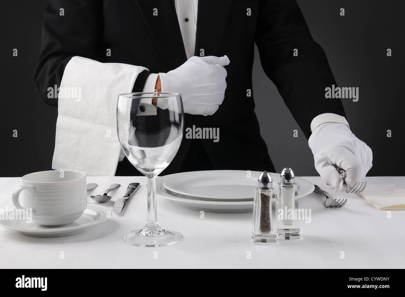 Primo piano di un cameriere in uno smoking impostazione di una cena formale tabella. Profondità di campo in formato orizzontale . Foto Stock