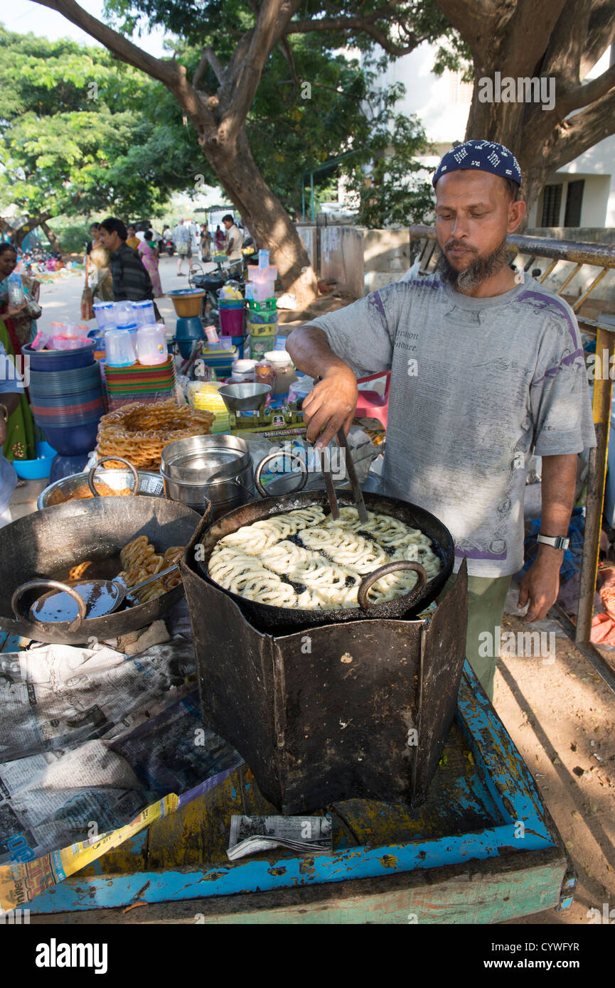 Uomo indiano la realizzazione e la vendita Jalebi [dolce Indiana] in un indiano street market. Puttaparthi, Andhra Pradesh, India Foto Stock