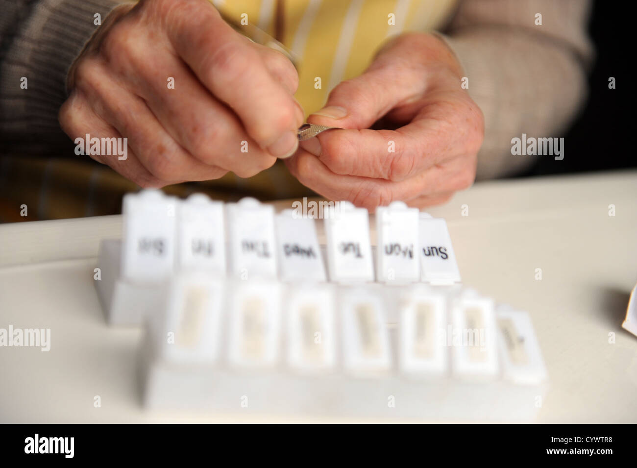 Anziano genitore mettendo la sua pillole nel suo porta pillole. Foto Stock