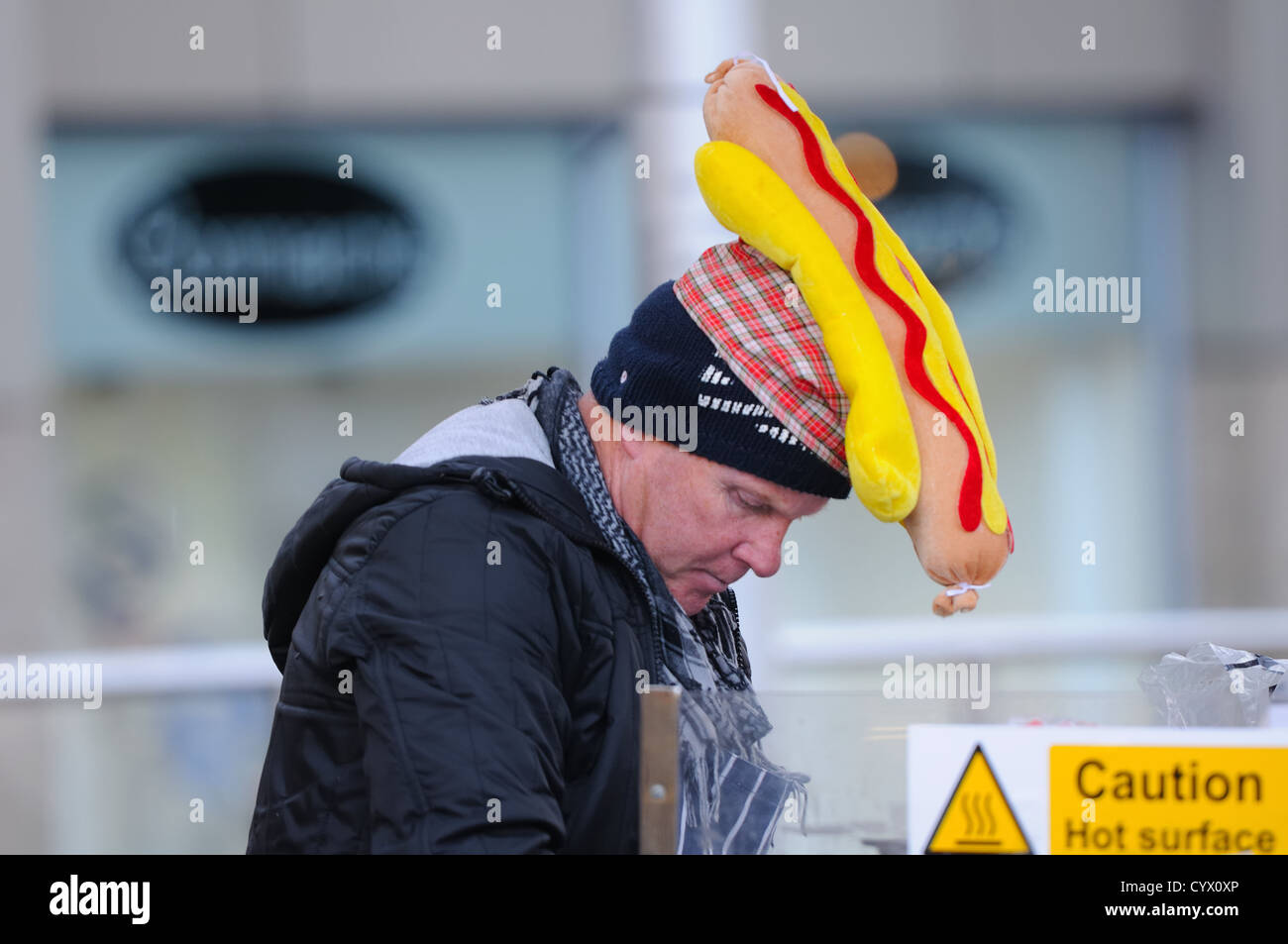 Venditore di Street food che indossa un divertente cappello da hot dog a Paisley, Scozia. Foto Stock