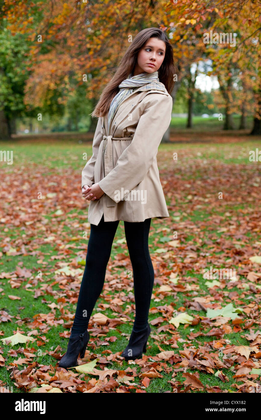 A piena lunghezza Ritratto di una bella donna in piedi su un campo coperto con autunno foglie d'oro, Green Park, London, England, Regno Unito Foto Stock