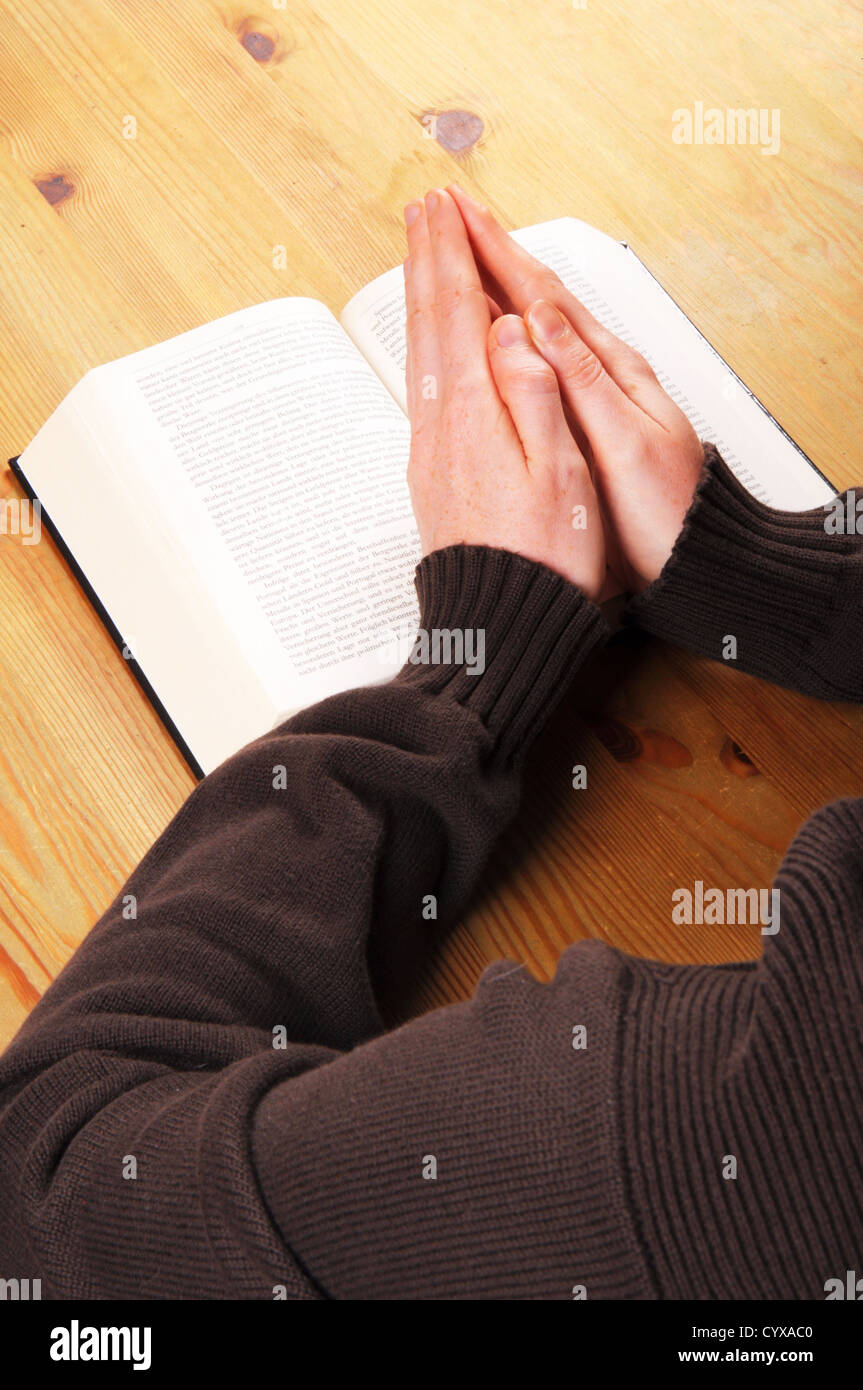 Pregando le mani e il libro che mostra la religione cristiana nozione Foto Stock