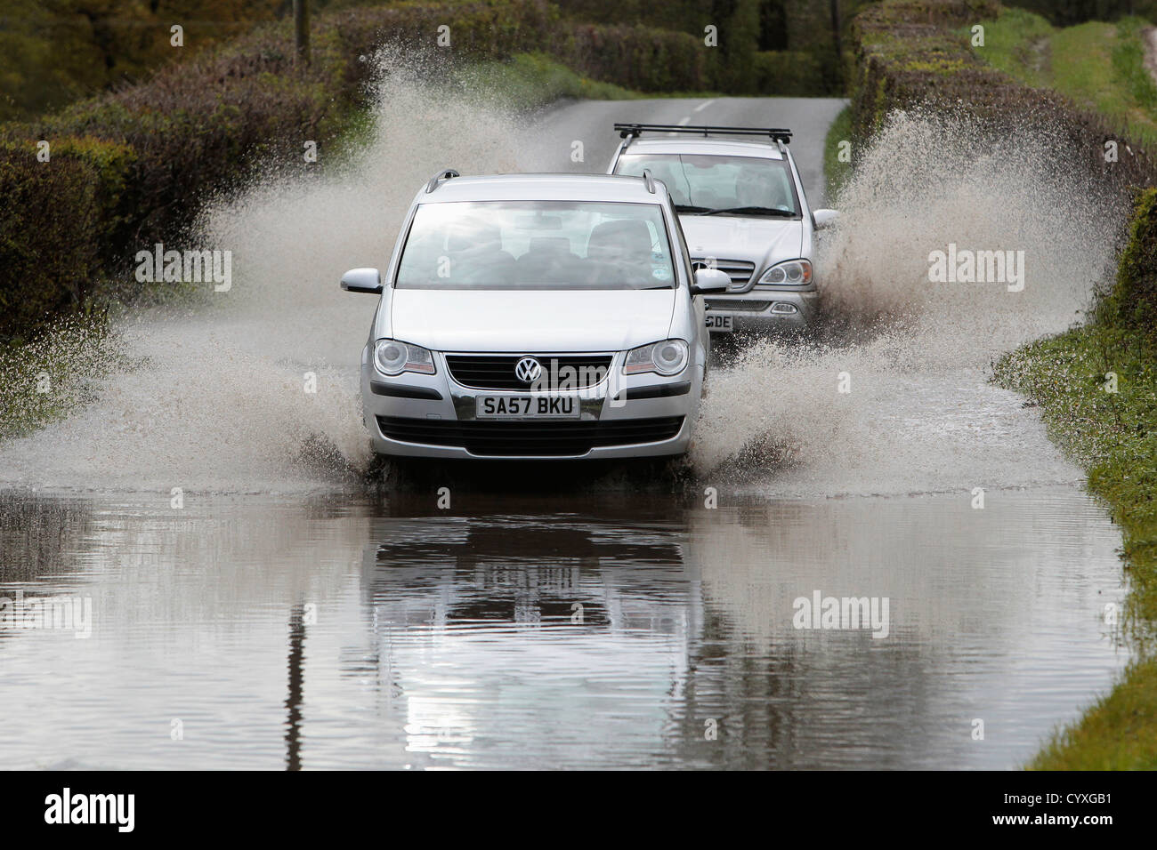 Allagato strade di campagna con auto guidando lentamente attraverso acque auto automobili Automobile Automóvil Automotive Autos British Foto Stock