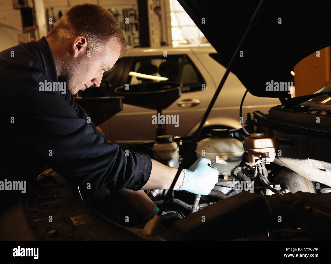 Riparatore lavorando su auto in garage auto automobili Automobile Automóvil Automotive Autos auto del cofano anteriore cofano uomini maschio Guy Foto Stock