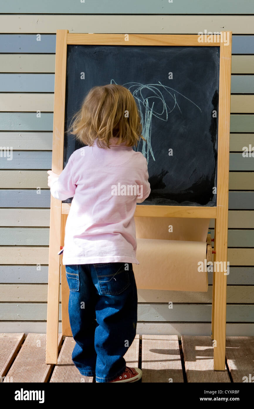 Carino giovane ragazzo caucasico scrivere su una lavagna nella scuola o asilo nido Foto Stock