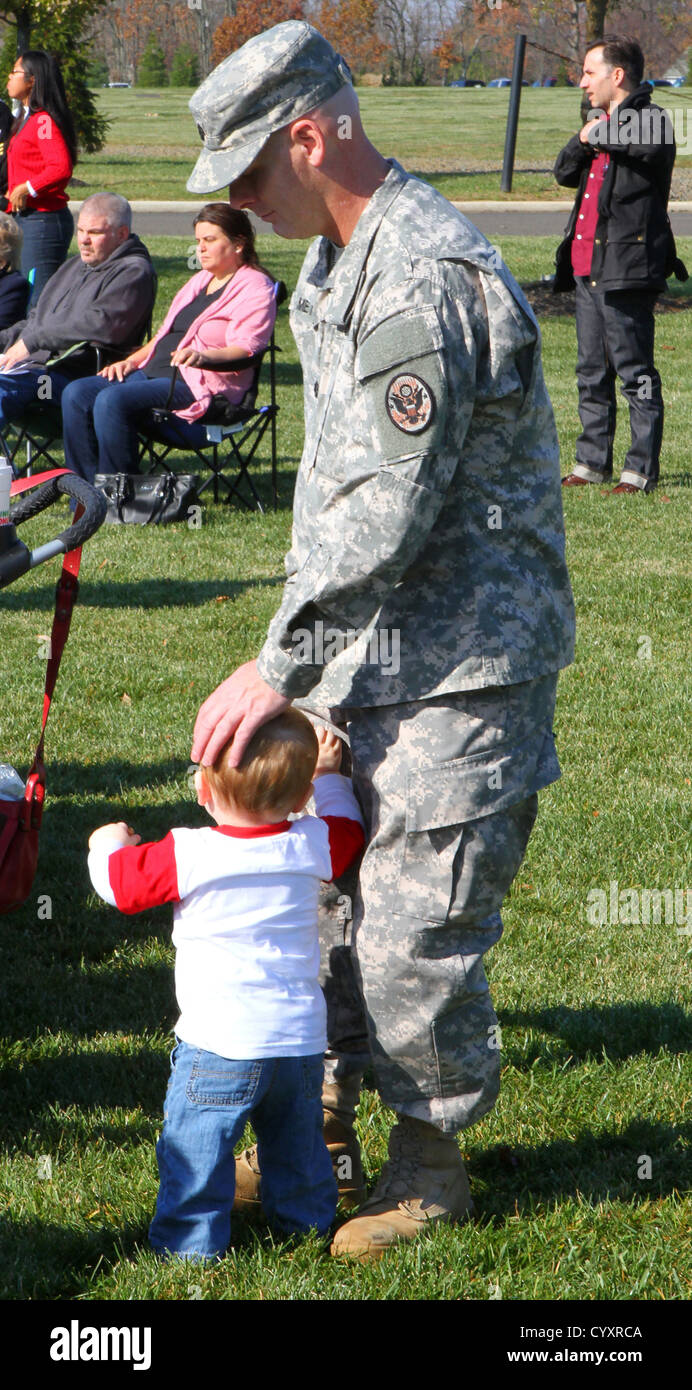 Un soldato della Guardia Nazionale del New Jersey conforta suo figlio durante un evento del Veterans Day, in quanto i leader militari onorano i membri del servizio recentemente mobilitati presso il Brigadier General William C. Doyle Veterans Memorial Cemetery. Foto Stock