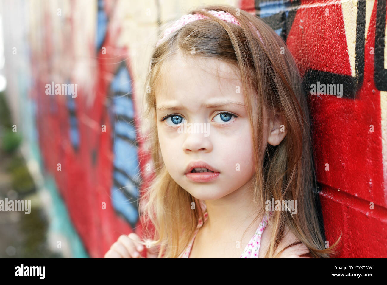 Preoccupato bambina in ambiente urbano cercando nella fotocamera. Foto Stock